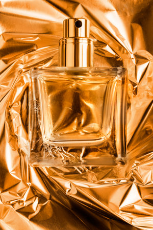 Transparent glass perfume bottle over crumpled golden foil backgroundの写真素材