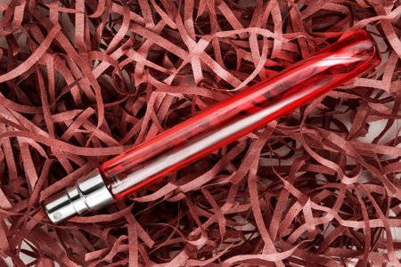 Red glass perfume vial lying in shredded packaging paperの写真素材