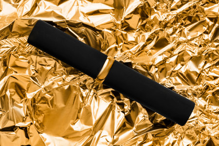 Elegant lipstick black tube lying on golden crumpled foil backgroundの写真素材