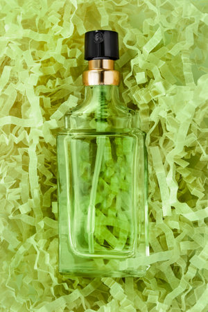 Vintage green perfume bottle lying in green sredded crinkle packaging paperの写真素材