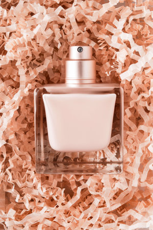 Beige perfume spray bottle lying on beige crinke shredded paperの写真素材