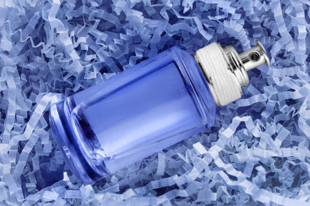 Blue perfume spray bottle lying in blue crinkle shredded paperの写真素材