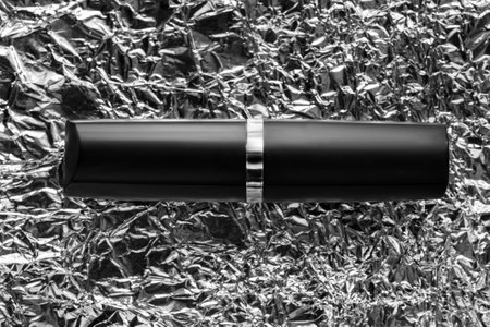 Black matte lipstick tube against silver foil crumpled backgroundの写真素材
