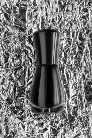 Black blank nail polish bottle against silver crumpled foil backgroundの写真素材