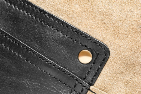 Black leather and beige suede bag details closeup as a background