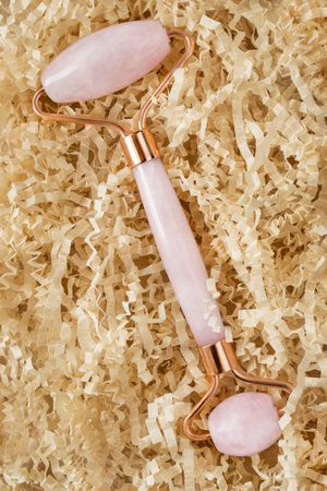 Rose quartz facial roller lying in crinkle packaging shredded paperの写真素材