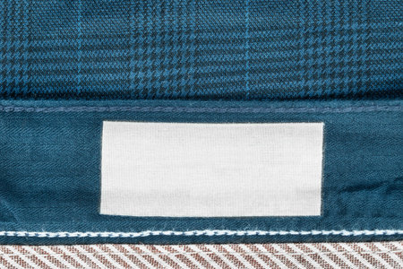 Blank clothes label frame on blue fabric background closeup