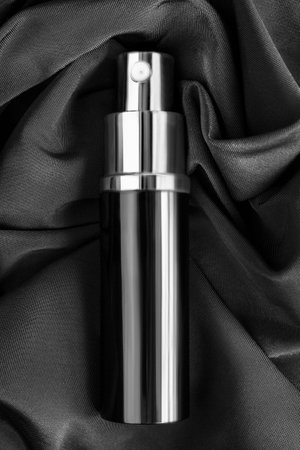 Perfume spray atomizer lying on black draped silk fabric backgroundの写真素材