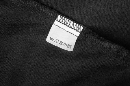 Care instructions clothes label stitched on black fabric background