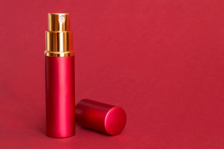 Red metallic perfume spray atomizer standing on red studio backgroundの写真素材