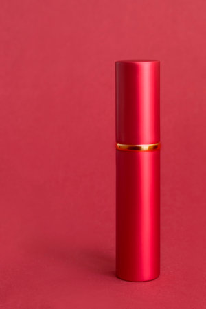 Red metallic lipstick tube case standing on red studio backgroundの写真素材