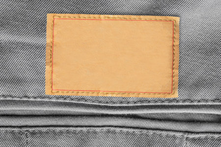 Empty clothes label stitched on gray denim fabric background closeupの写真素材