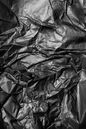 Black crumpled wrapping paper closeup as a backgroundの写真素材