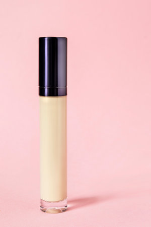Natural beige tone concealer tube standing on pastel pink studio backgroundの写真素材