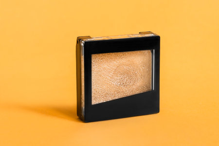 Golden glitter eyeshadows box on yellow color studio backgroundの写真素材