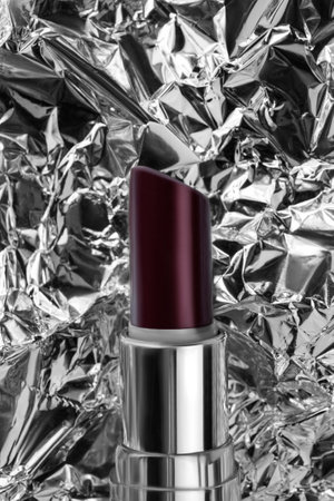 Dark burgundy color lipstick closeup on crumpled silver foil backgroundの写真素材