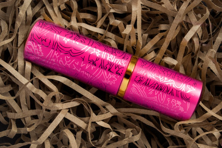 Pink metallic lipstick case lying in brown shredded packaging paperの写真素材