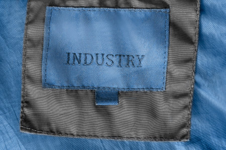 Clothes patch label says industry stitched on black and blue fabric backgroundの写真素材