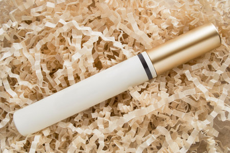 Blank mascara tube lying on crinkle shredded packaging paper backgroundの写真素材