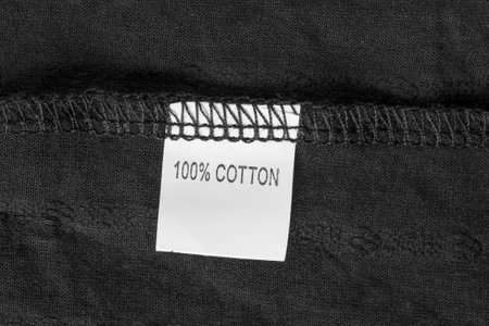 Clothes label says 100% cotton stitched on black fabric closeupの写真素材