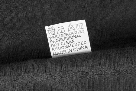 Care instructions clothes label says made in China on black cotton fabric backgroundの写真素材