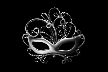 Silver brooch in the shape of venetian mask isolated on black backgroundの写真素材
