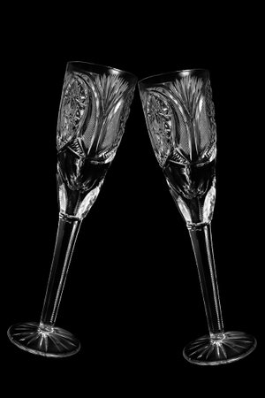 Two clinking vintage crystal empty champagne glasses isolated on black backgroundの写真素材