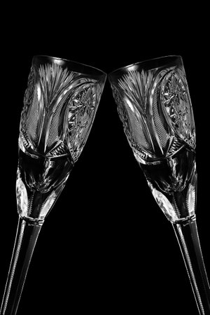 Two clinking vintage crystal empty wineglasses closeup isolated over blackの写真素材