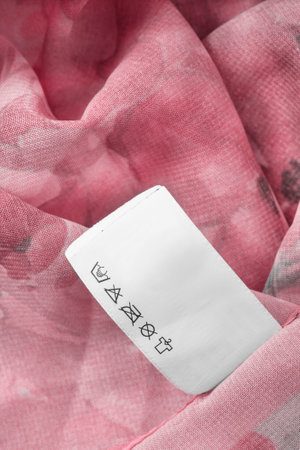 Washing instructions clothes label on pink chiffon fabric background closeupの写真素材