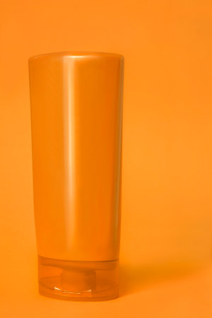 Orange color plastic blank shower gel bottle standing on orange studio backgroundの写真素材