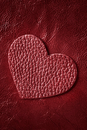 Red leahter blank heart over dark red leatherette backgroundの写真素材