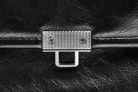 Metallic bag clasp on black leather closeup as a backgroundの写真素材