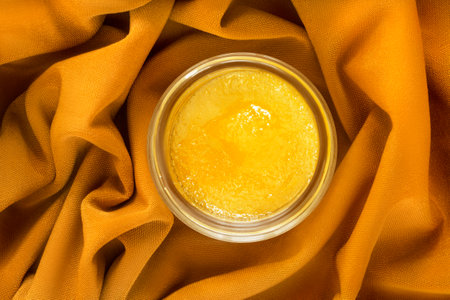 Yellow sugar lip scrub jar over yellow draped fabric backgroundの写真素材