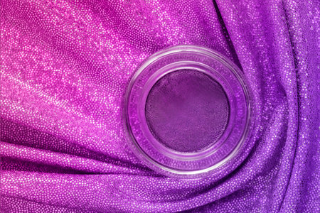 Purple eyeshadows jar over pink and purple holographic draped fabricの写真素材