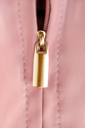 Zipper with golden lock in pastel pink fabric closeup as a backgroundの写真素材