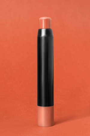 Brown concealer stick standing on brown color studio background