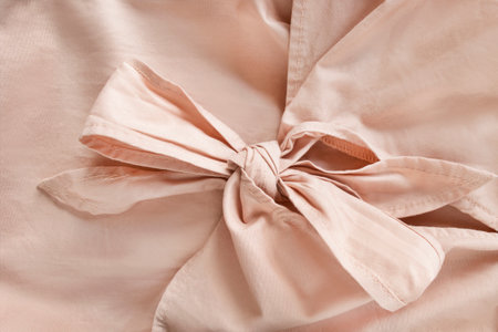 Tied bow detail of beige cotton fabric garment closeup as a backgroundの写真素材