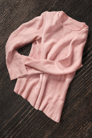 Pastel pink cashmere pullover lying on dark brown wooden backgroundの写真素材