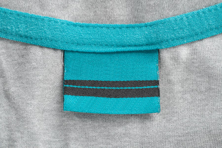 Blank blue clothes label over gray knit fabric background closeup