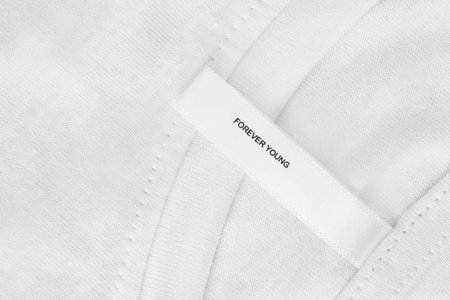 Clothes label with text forever young over white fabric background