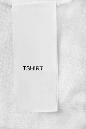Clothes label says T-Shirt over white cotton fabric background closeupの写真素材