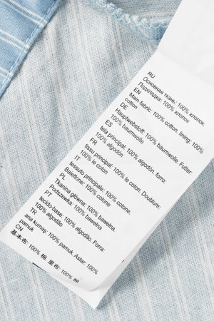Fabric composition label in different languages closeup over light blue fabricの写真素材