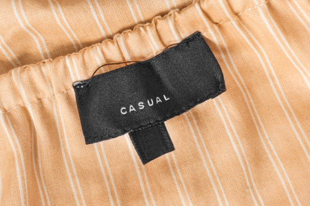 Black casual clothes label stitched on yellow striped cotton backgroundの写真素材