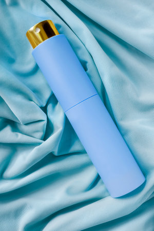 Perfume spray atomizer lying on light blue draped silk fabric backgroundの写真素材