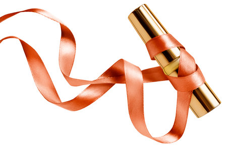 Luxury golden lipstick case tube wrapped with satin ribbon isolated over whiteの写真素材