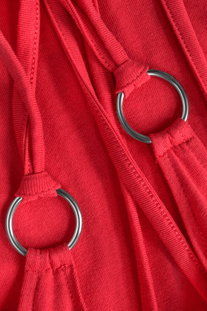 Red cotton fabric straps and laces with metallic rings closeup as a backgroundの写真素材