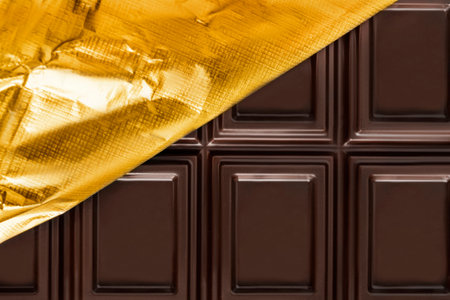 Dark chocolate unwrapped golden foil closeup as a backgroundの写真素材