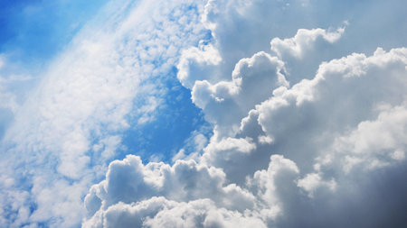 Beautiful fluffy white clouds in blue sky highlighted by the sunの写真素材