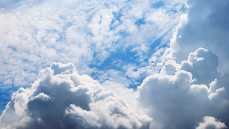 Beautiful fluffy large clouds in blue sky highlighted by the sunの写真素材