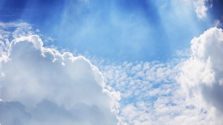 White fluffy clouds in blue sky highlighted by the sunの写真素材